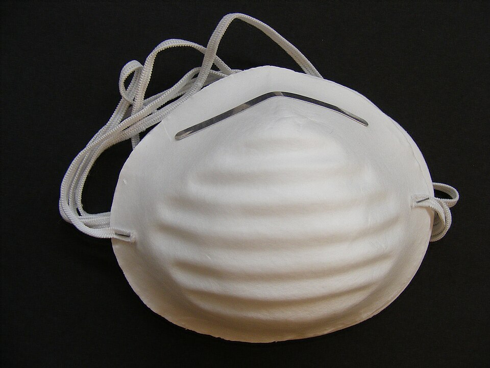 A white cone-shaped dust mask with a single thin elastic strap and a metal nose strip